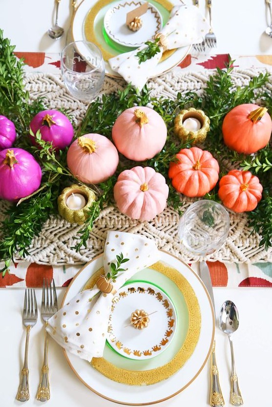 a colorful and glam Thanksgiving tablescape with a greenery and macrame runner, white gold rimmed plates, colorful pumpkins