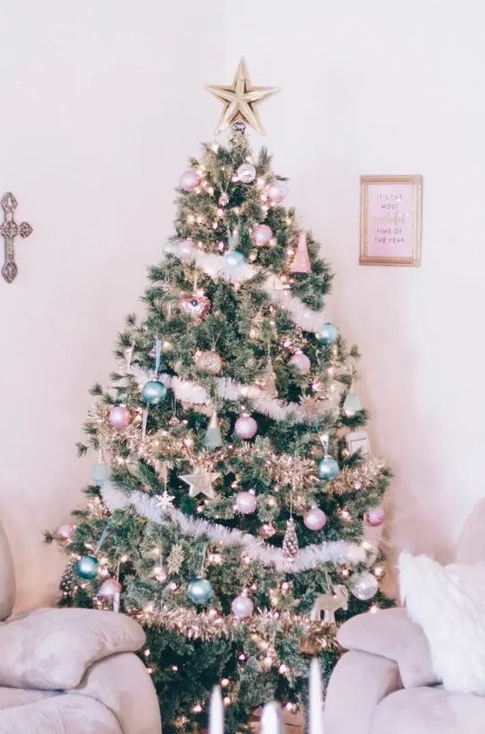 a Christmas tree decorated with pastel green and pink ornaments, stars, lights and fluffy garlands plus a star topper