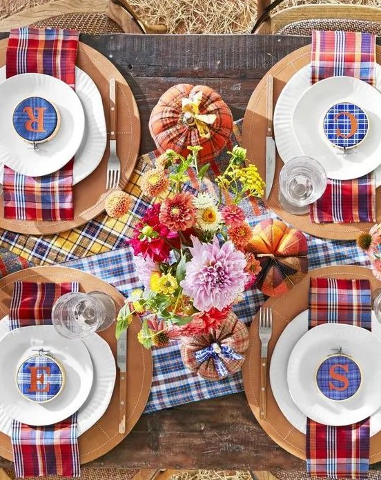 a colorful Thanksgiving tablescape with bright plaid table runners and napkins, plaid embroidery hoops, bright flowers and plaid pumpkins