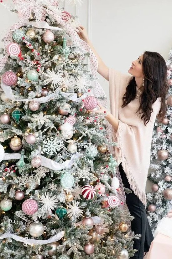 a Christmas tree with pastel pink and green ornaments, gold and silver ones, striped ribbons and snowflakes and stars