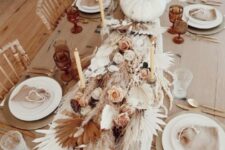 30 a gorgeous boho Thanksgiving tablescape with gold placemats and white porcelain, a lush table runner made of pampas grass, fronds, a white pumpkins, pink and white blooms