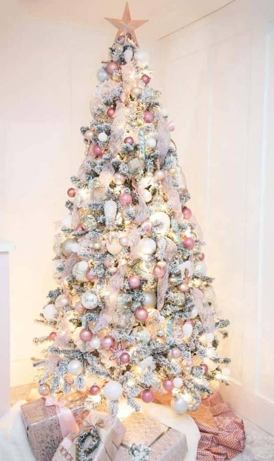 a flocked Christmas tree decorated with neutral, pink, silver ornaments, blush ribbon and a pink star topper