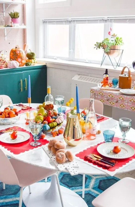 a fun and colorful fall decorated space with super bold veggies and fruits, colorful candles, pumpkins and glasses and placemats