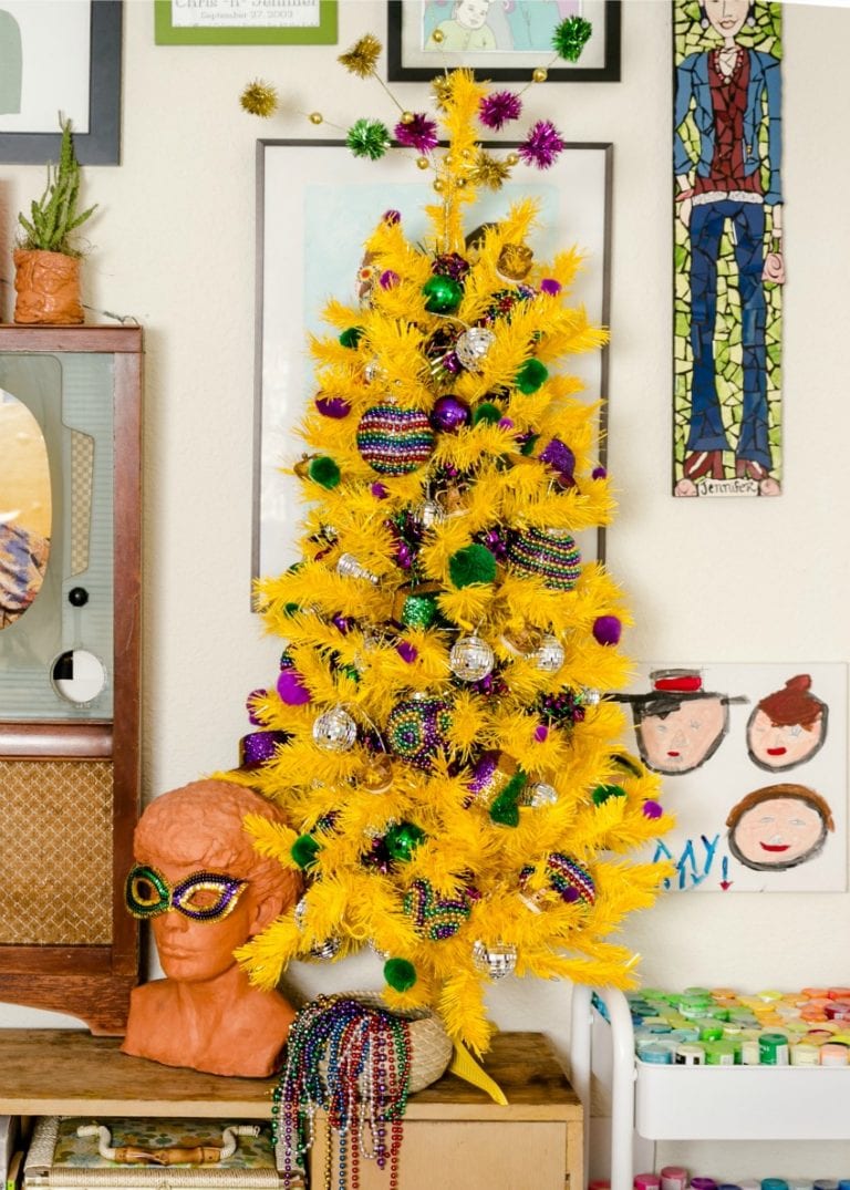 a yellow Christmas tree styled with green, silver and purple ornaments looks super fun, bold and chic