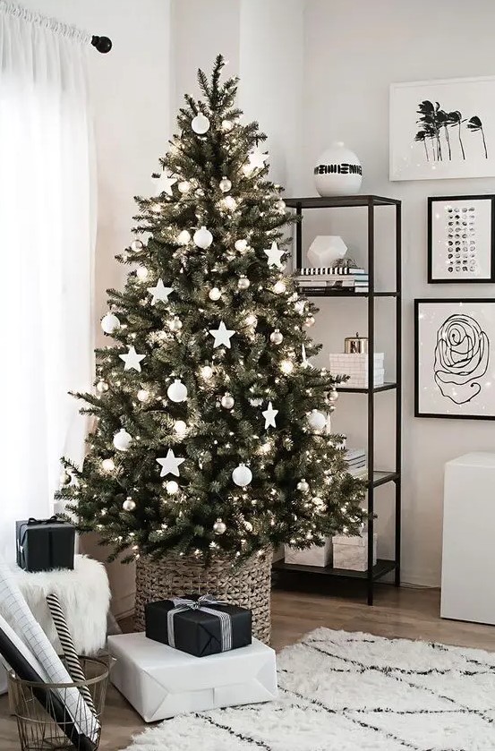 a Scandinavian Christmas tree decorated with white ball and star ornaments, metallic ornaments plus lights in a basket