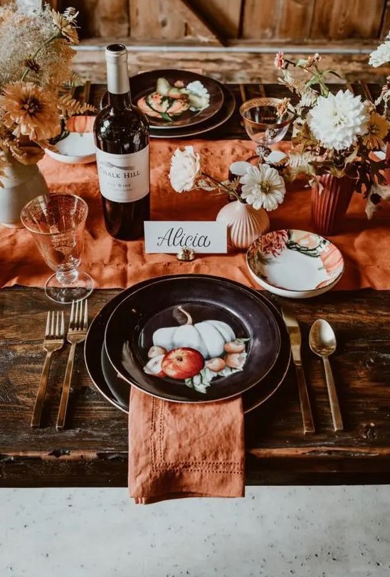 a pretty rust-colored Thanksgiving tablescape with rust linens and vases, dried and fresh blooms, painted black plates