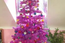 38 a purple Christmas tree decorated with bold ornaments and topped with a colorful tree topper is awesome