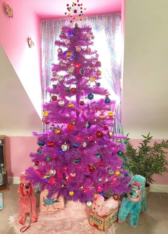 a purple Christmas tree decorated with bold ornaments and topped with a colorful tree topper is awesome