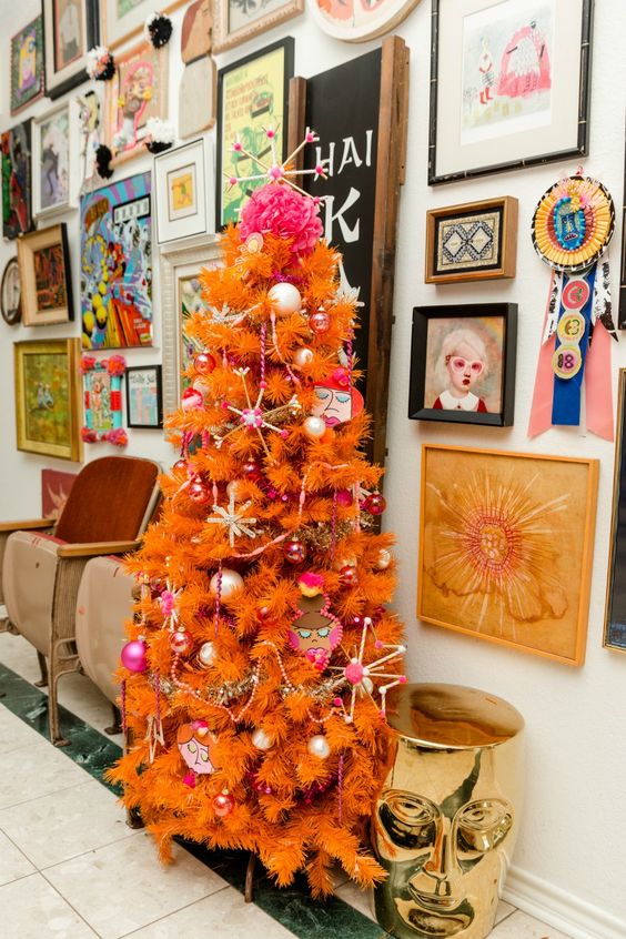 an orange Christmas tree with whimsical ornaments and beads is a lovely idea for a bold and quirky space