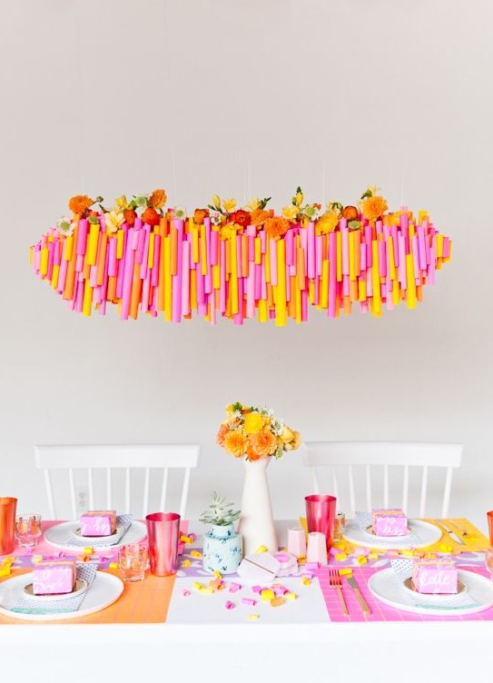 a super bright Thanksgiving tablescape with bold placemats, colorful glasses and blooms, a bold overhead installation with blooms