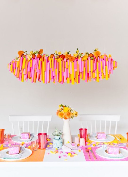 a super bright Thanksgiving tablescape with bold placemats, colorful glasses and blooms, a bold overhead installation with blooms
