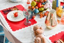 43 a super colorful Thanksgiving table setting with red placemats, blue candles, colorful faux veggies and blue glasses