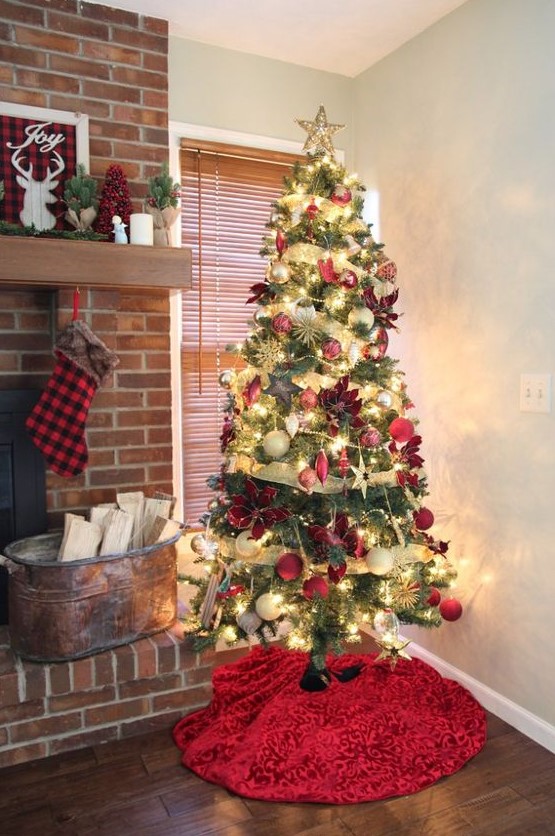 a Christmas tree with lights, gold ribbons, red, neutral and gold ornaments, poinsettia and stars