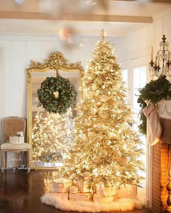 a gold pre-lit Christmas tree with white ornaments and a faux fur skirt is a super glam and shiny idea for the holidays