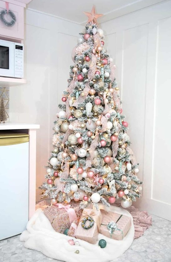 a flocked Christmas tree done with ribbon, pink, blush, white and gold ornaments, a pink star on top and some lights