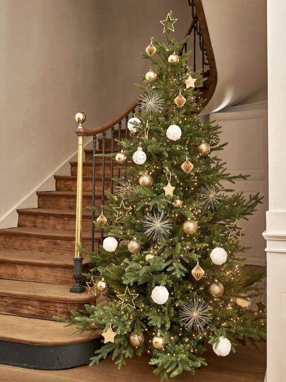 a stylish Christmas tree decorated with gold, white and brown ornaments of various shapes, with lights and stars