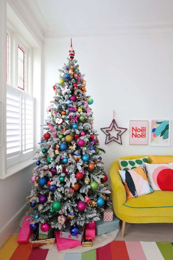 a flocked Christmas tree decorated with super colorful ornaments and rainbows is a gorgeous idea for a bold space