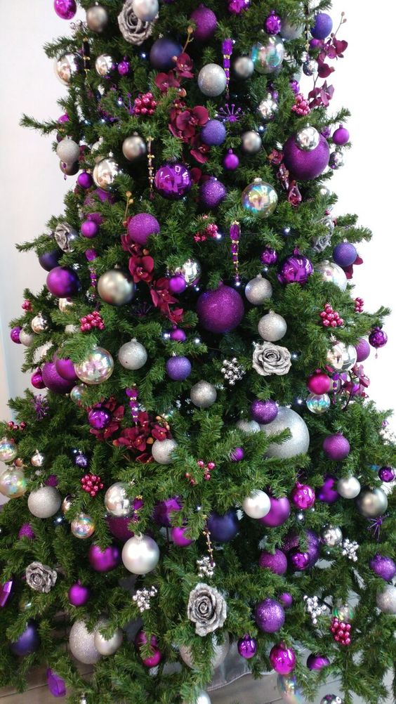a Christmas tree decorated with silver, purple, hot pink, pearl and other ornaments and fabric blooms is chic