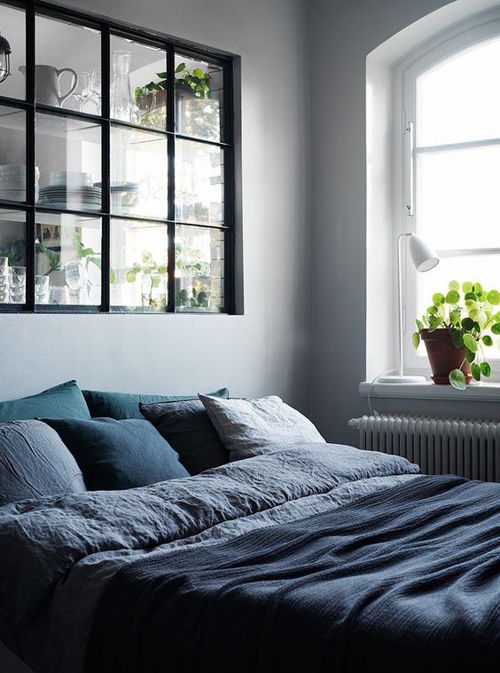 a Scandinavian bedroom connected to the kitchen with a large window with a black frame looks peaceful and light-filled