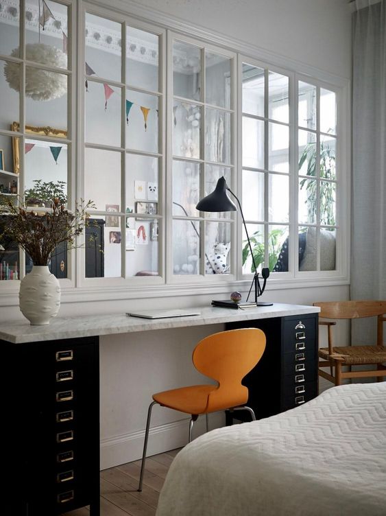 a bedroom with an integrated workspace gets more natural light from the kids' room through a large window