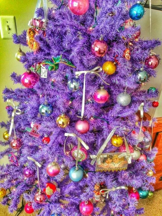 a bright purple Christmas tree decorated with super colorful Christmas ornaments on ribbon bows plus lights is a whimsical solution