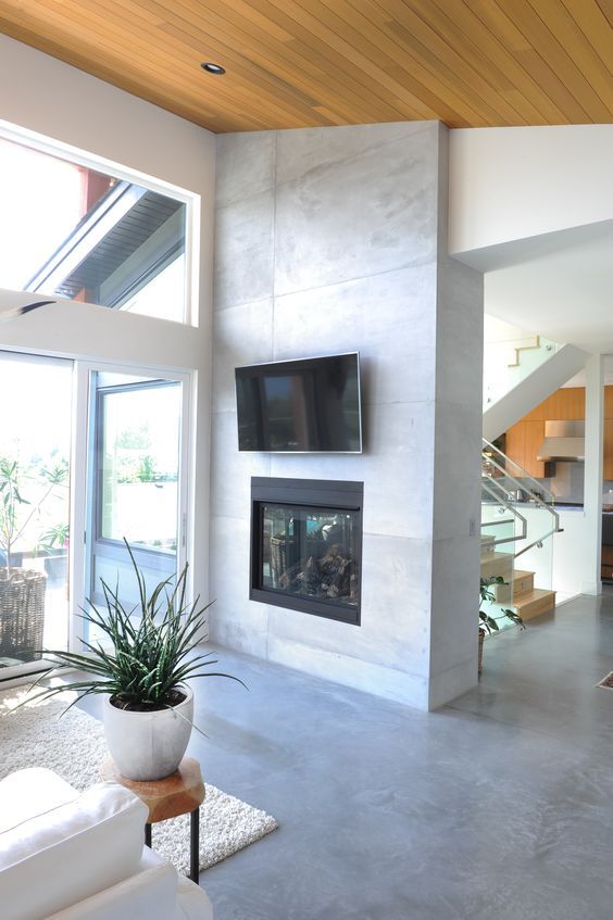 a built-in concrete fireplace with a TV over it gives warmth and light to the staircase space and living room