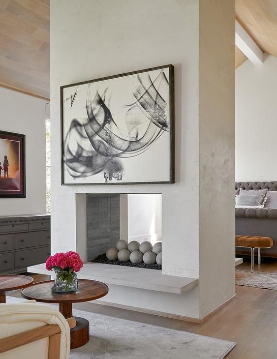 a cocnrete double-sided fireplace gives warmth and coziness to both bedroom and living room and separates the spaces