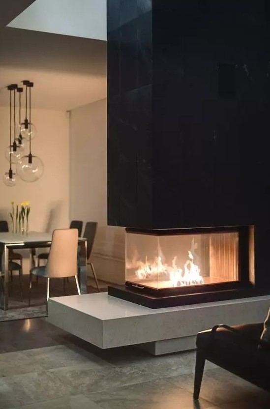 a contemporary double-sided fireplace with a sleek black tile top and a light-colored stone base is a bold contrasting idea to rock