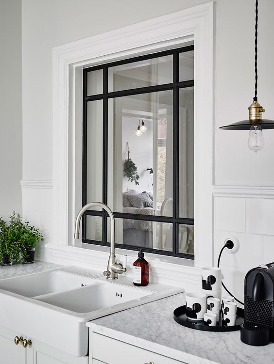 a cozy Scandinavian kitchen with a window with black frame to the bedroom to let more light inside both spaces