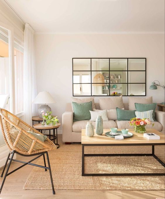 a cozy light-filled living room with a black framed window that leads to the kitchen and connects both spaces