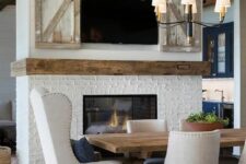 a double-sided fireplace clad with brick and a TV over it is a cozy feel and welcoming touch to the dining and living room