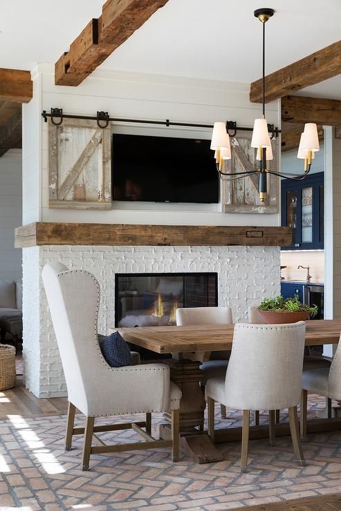 a double sided fireplace clad with brick and a TV over it is a cozy feel and welcoming touch to the dining and living room