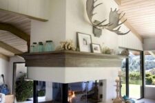 a double-sided fireplace with a wooden mantel and decor located between the living room and entryway