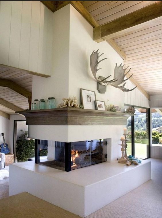 a double sided fireplace with a wooden mantel and decor located between the living room and entryway