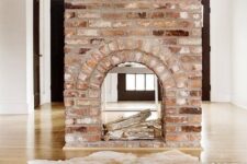 a gorgeous double-sided fireplace clad with brick looks very vintage and brings a character and a story to the room