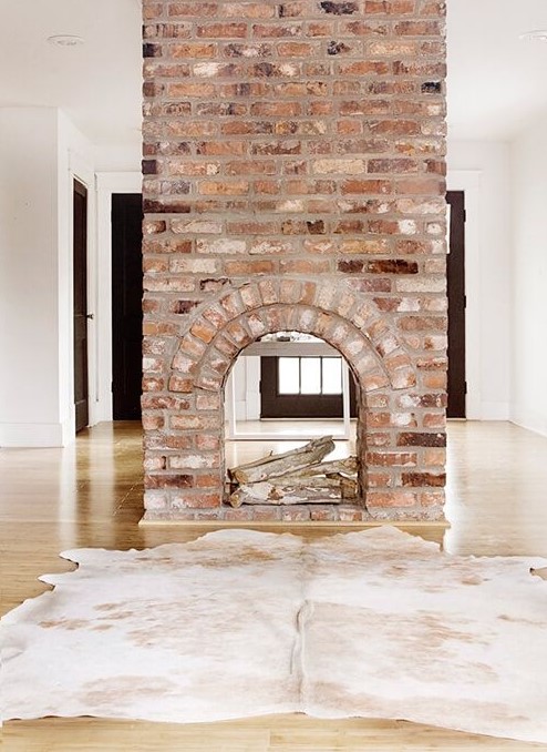 a gorgeous double-sided fireplace clad with brick looks very vintage and brings a character and a story to the room