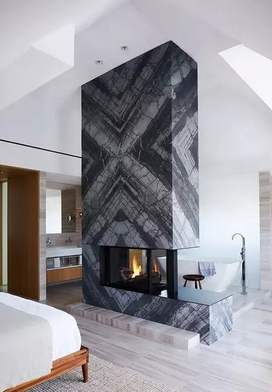 a grey marble slab double-sided fireplace separates the sleeping and bathing zone and makes them cozy and warm