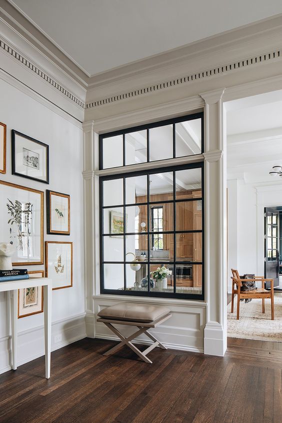 a large French window with black framing connects the living room and the entryway and lets more natural light inside