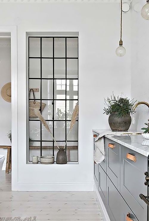 a large window from the kitchen to the entryway gives natural light to this small space and makes it more welcoming
