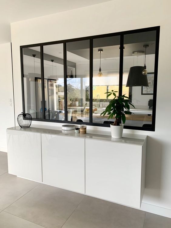 a large window with black frames allows to fill the entryway with natural light coming from the kitchen