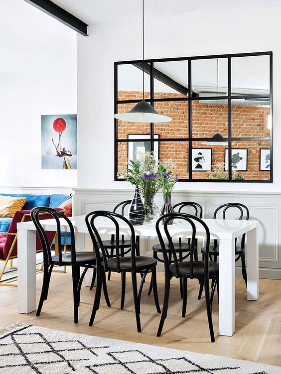 a large window with black frames that separates the dining room and kitchen and gives more light to both zones