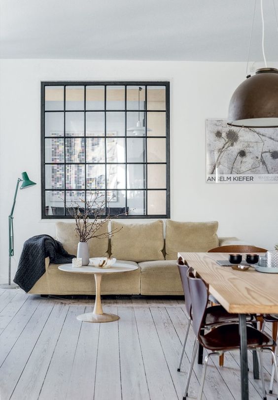 a living and dining room connected to the entryway with a large French window with black frames give some light to the entry