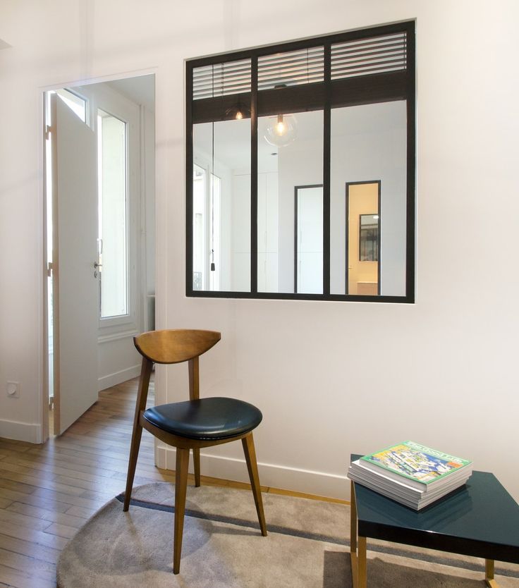 a living room is connected to the next space with a window with a black frame looks stylish and lets light in