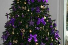 a luxurious Christmas tree decorated with bold purple bows and stars and gold ornaments and bows is a chic idea