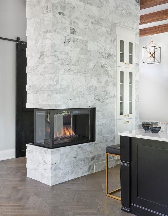 a marble double-sided fireplace to illuminate and warm up the kitchen and the entryway is a cool idea to add coziness
