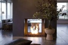 a modern double-sided fireplace done of grey concrete looks really spectacular and very chic