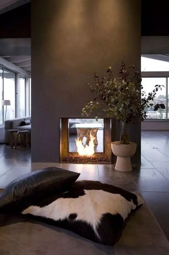 a modern double-sided fireplace done of grey concrete looks really spectacular and very chic