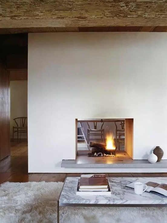 a modern white double sided fireplace with a concrete stand is a cozying up and chic idea for a modern space
