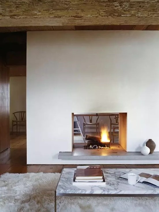 a modern white double-sided fireplace with a concrete stand is a cozying up and chic idea for a modern space