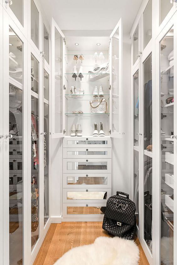a narrow walk in closet with glass doors, with open cabinets and shelves, with mirror drawers is a glam and refined idea